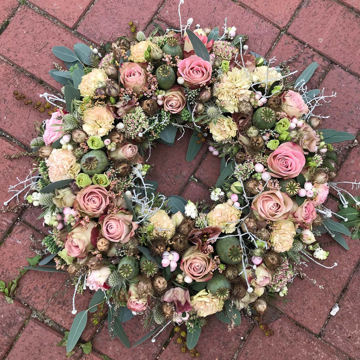 Begravelsesbinderi. Rundpyntet krans i rosa nuancer.