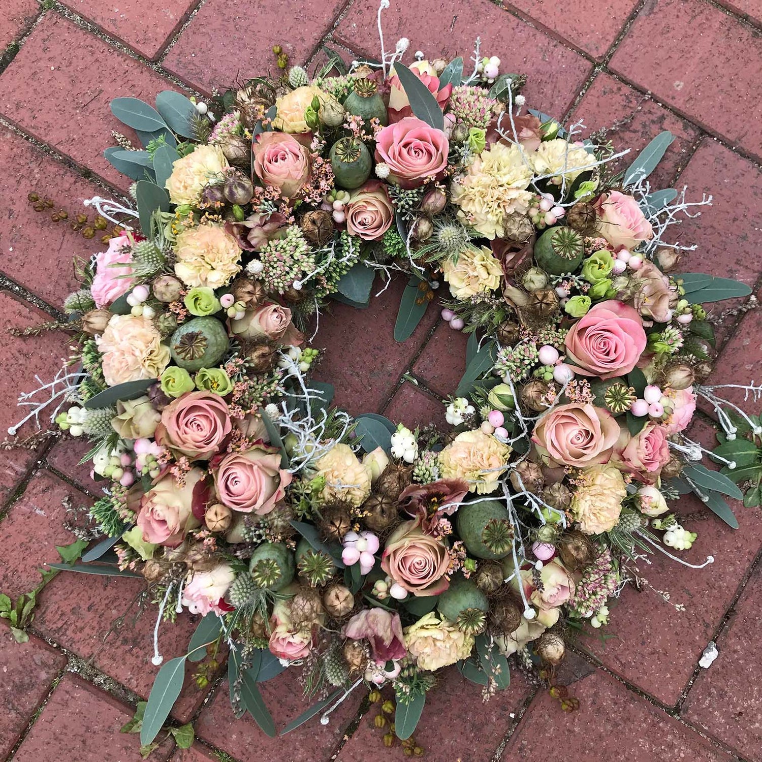 Begravelsesbinderi. Rundpyntet krans i rosa nuancer.