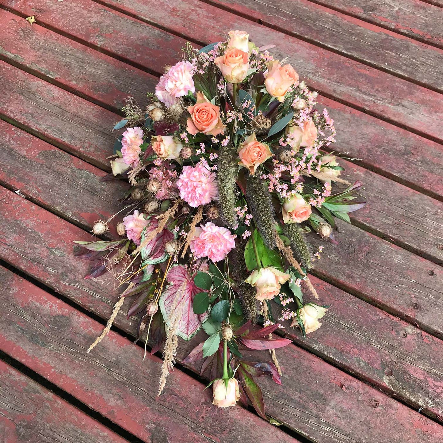 Aflang båredekoration i rosa nuancer. Begravelsesbinderi.