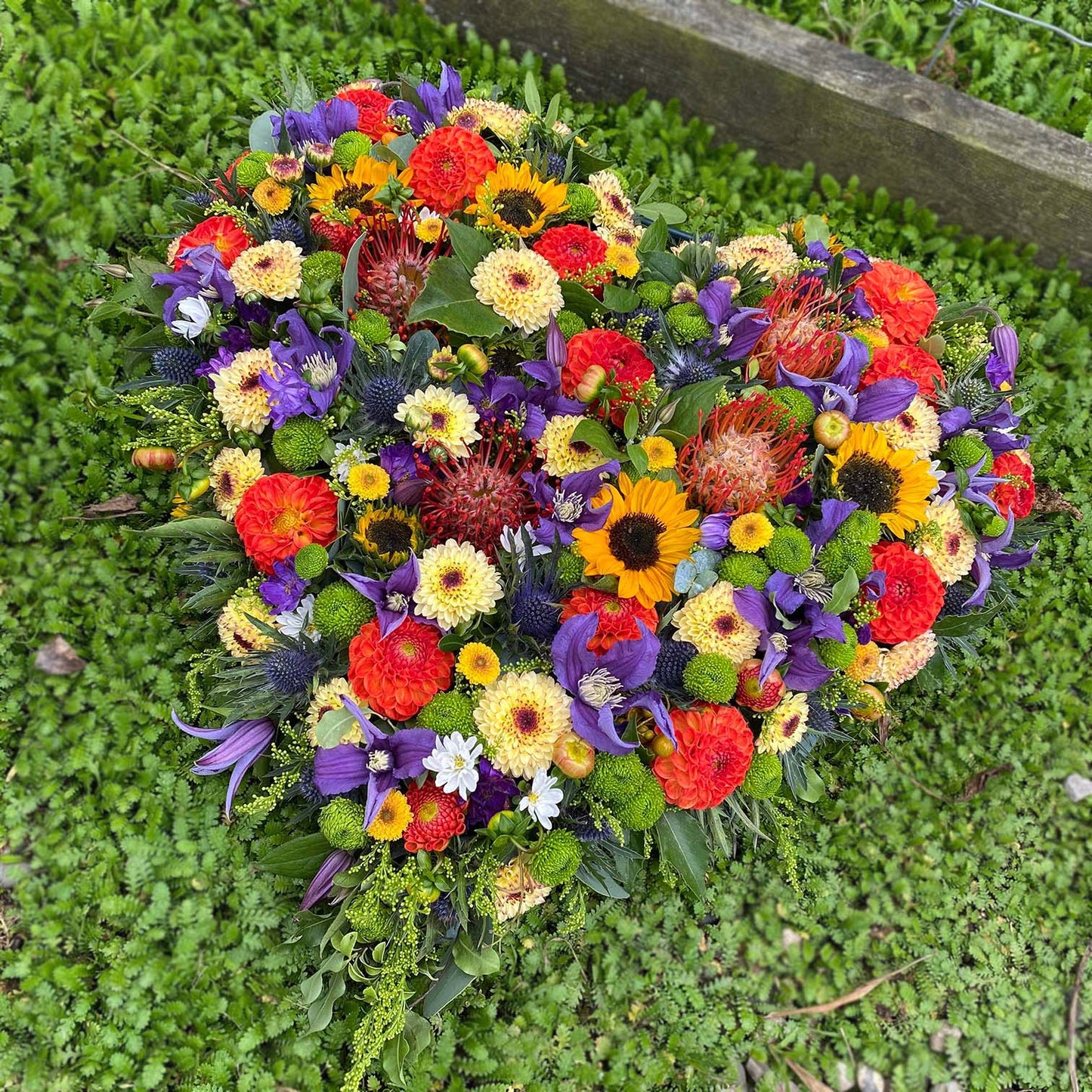 Hjerte dekoreret med afskårne blomster i forskellige nuancer. Begravelsesbinderi.