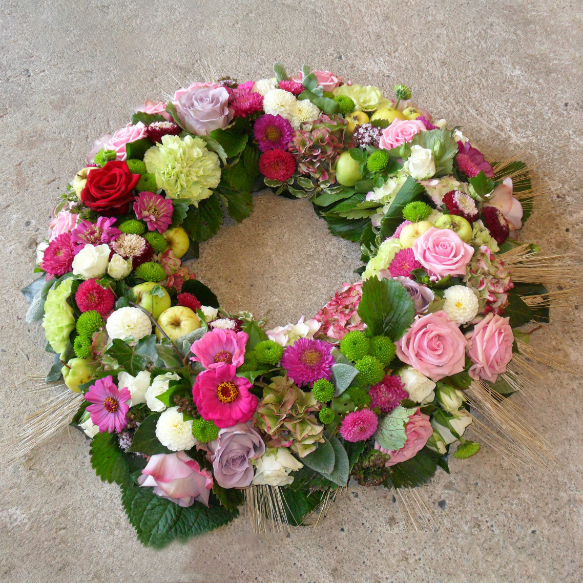 Begravelsesbinderi. Rundpyntet krans i rosa nuancer.