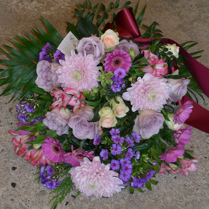 Bårebuket med bånd i pastelfarver. Begravelsesbinderi.