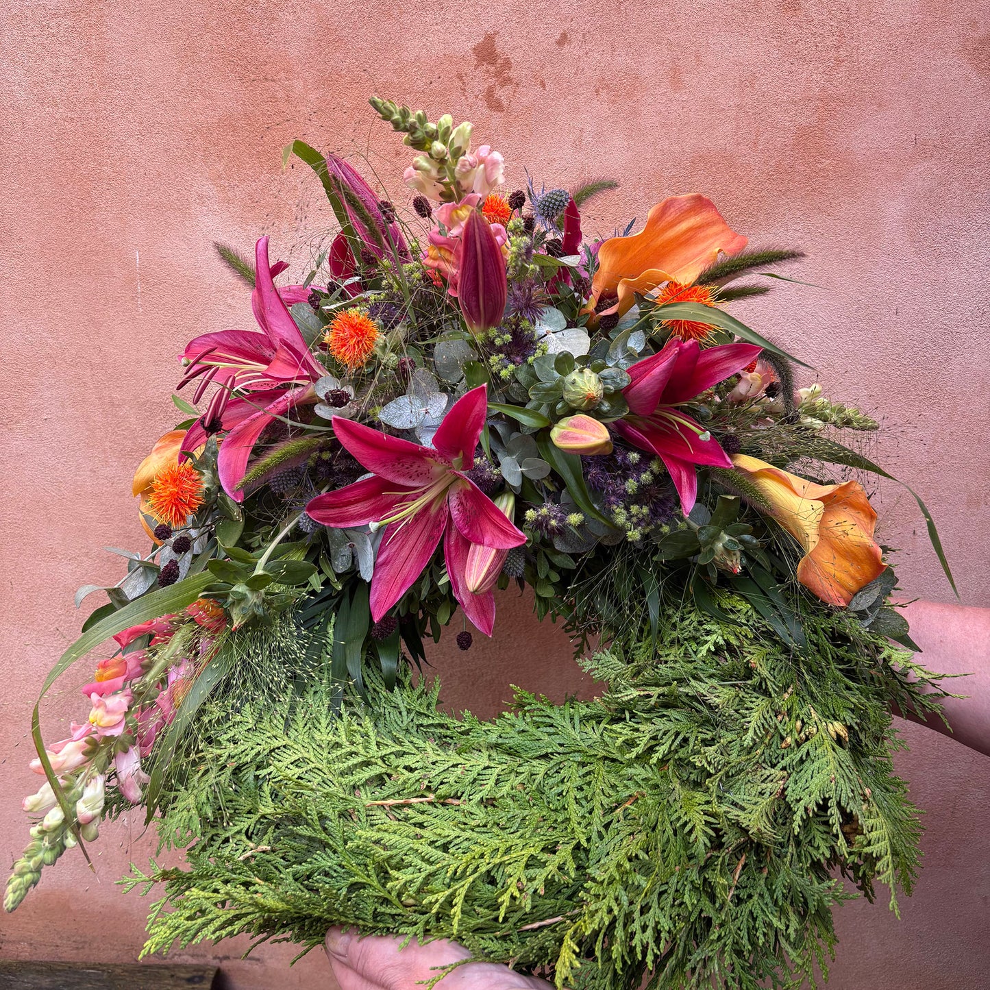 Krans thuja med afskårne blomster i røde og orange farver