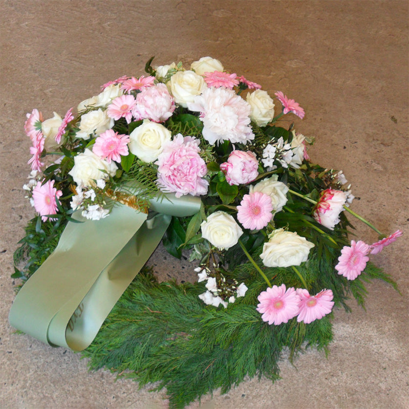 Begravelsesbinderi. Thujakrans med dekoration i rosa nuancer og bånd